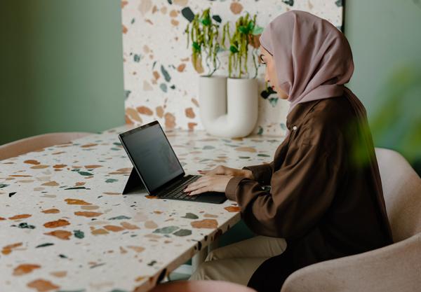 Woman wearing hijab typing on a laptop